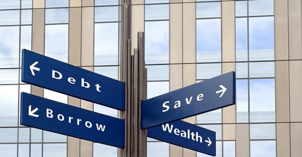 Street signs pointing to different and labelled Debt, Save, Borrow, Wealth